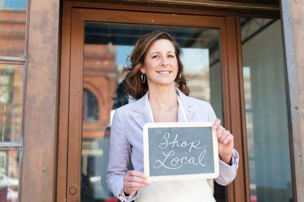 A woman holding a shop local sign